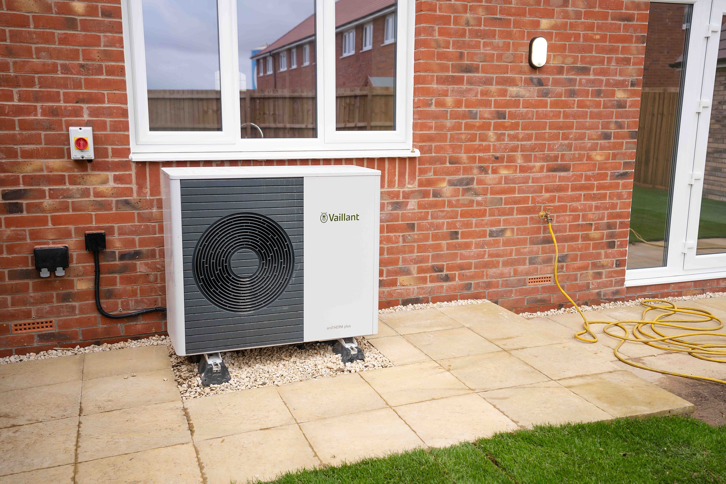 An air source heat pump fitted by HRB Mechanical Services outside a brick house